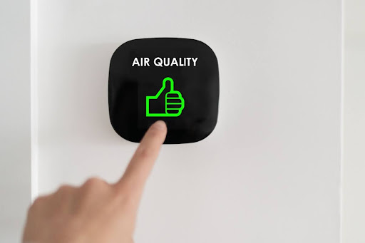 A finger pressing a button that says "air quality" with a thumbs up icon.