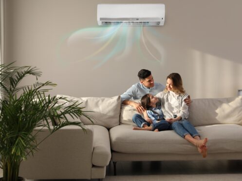 Couple sitting on couch under ductless AC blowing out cold air.
