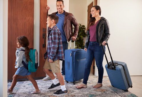 A family with luggage leaving their house to go on vacation.